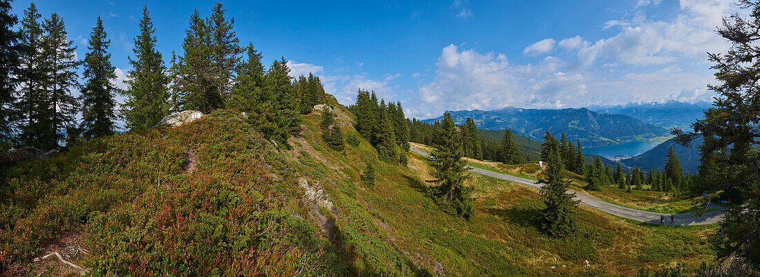 View from Mount Schüttenhöhe with hikers on trail in the mountains above Zell am See, Kaprun; Salzburg State, Austria