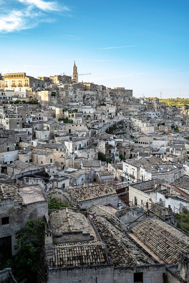 Cityscape of the mountaintop town of Sassi di Matera and its ancient cave dwellings with the bell tower of the Matera Cathedral overlooking the city; Matera, Basilicata, Italy
