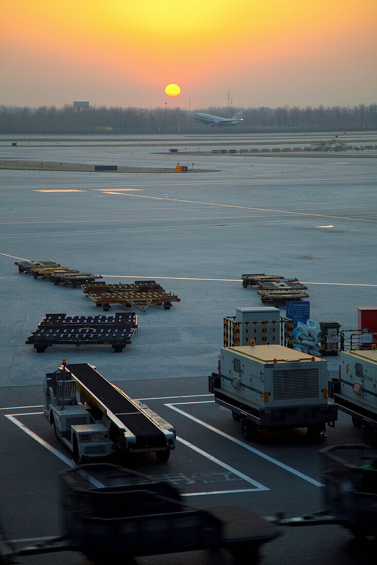 Sonnenaufgang über der Ausrüstung auf dem Rollfeld des Pekinger Flughafens; Peking Thailand