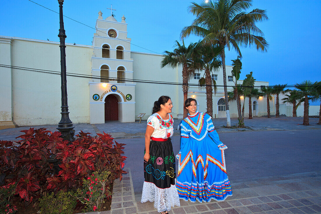 Frauen in traditionellen folkloristischen Kleidern am frühen Morgen in der Innenstadt von Todos Santos Baja California Sur, Mexiko.
