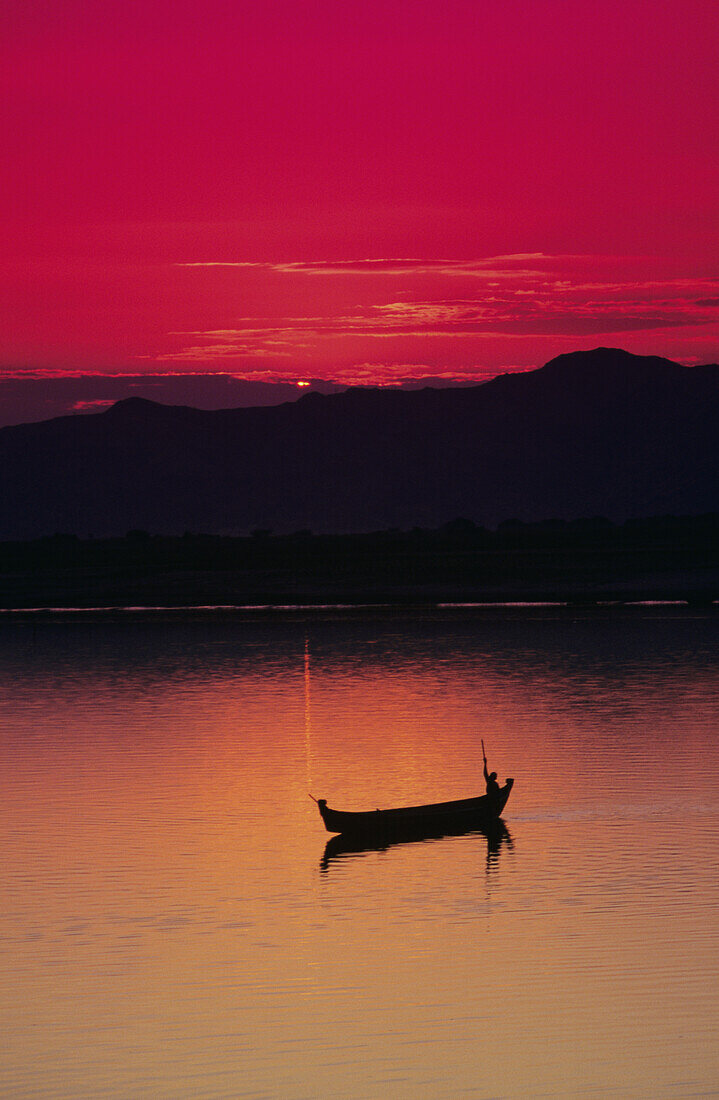 Myanmar (Burma), Bagan, Irrawaddy River, Fisherman In Boat Silhouetted Against Bright Red Sunset.