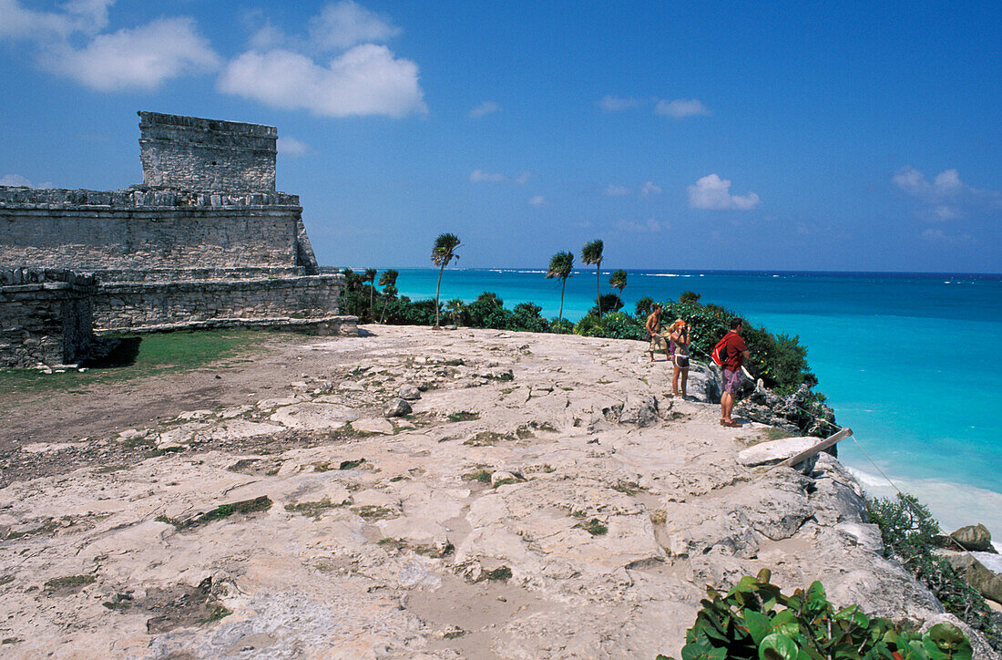 Mexico, Yucatan Peninsula, Visitors standing on rocky cliff near ruins; Tulum