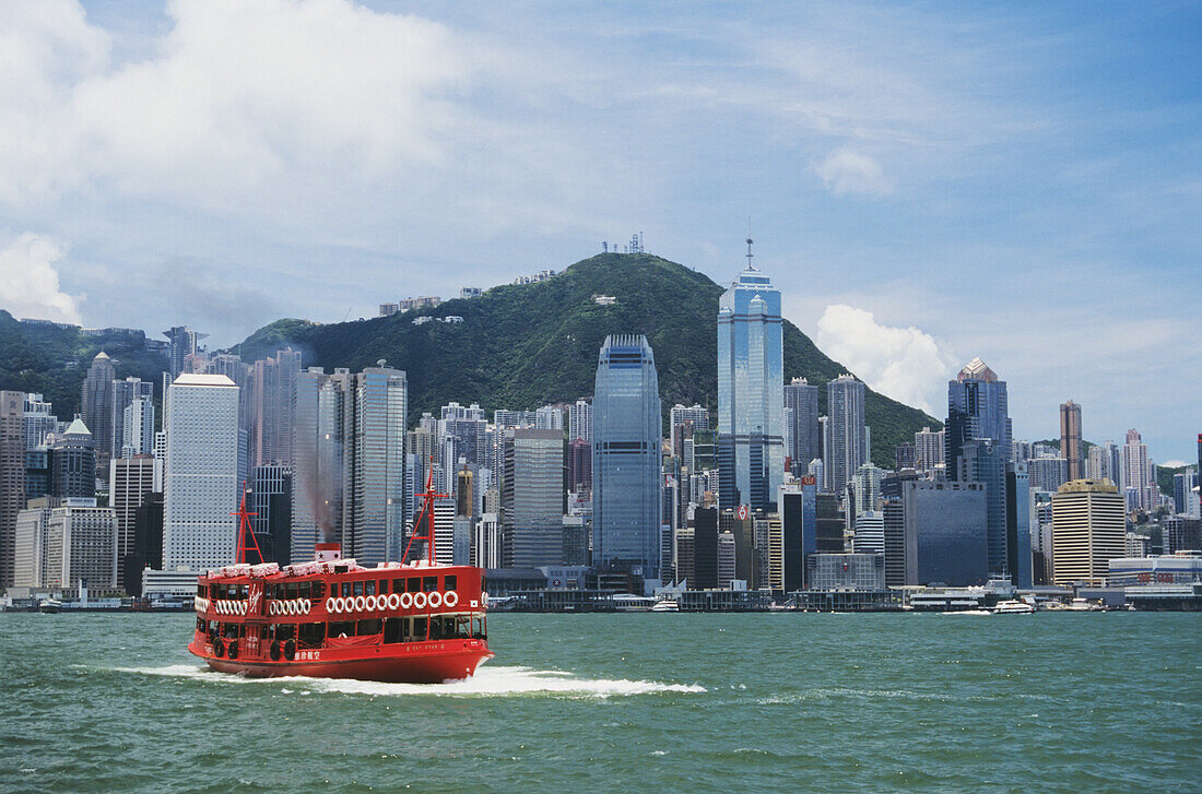 China, Hongkong, Blick auf Geschäftsviertel mit großer roter Virgin Atlantic-Fähre im Vordergrund; Hafen von Hongkong