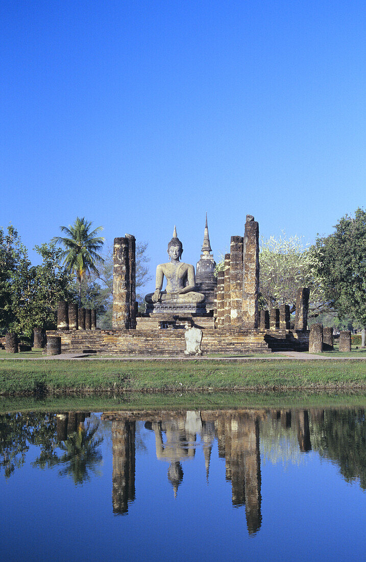 Thailand, Sukhothai, Buddha-Statue und Säulen spiegeln sich im Teich; Wat Mahathat