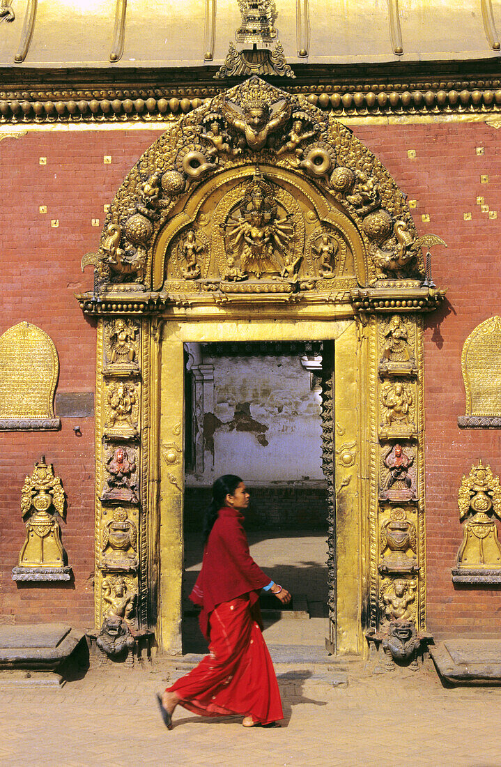 Nepal, Bhaktapur, Durbar Square, Local Woman Walking Past Golden Gate, Afternoon Lighting.