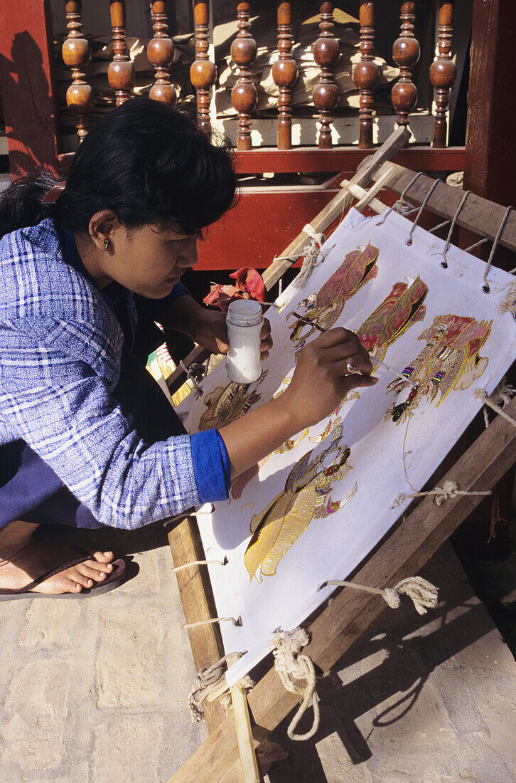 Burma (Myanmar), Mandalay, Local Woman Handpainting Kalaga Tapestry In Shop, View From Side.