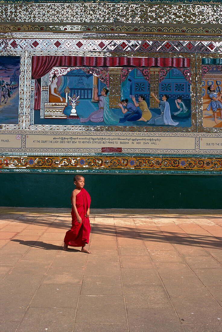 Burma (Myanmar), Blick auf einen Mönch, der durch einen Tempelhof mit gemalten Reliefs geht
