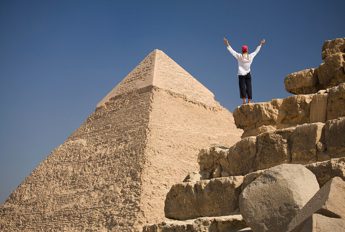 A Woman Tourist Raises Her Arms In Front Of The Pyramids Of Giza Near Cairo; Giza Egypt