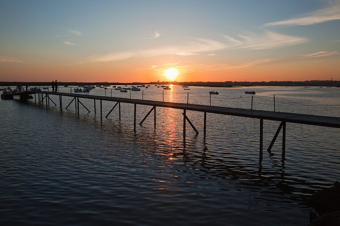 Ein Pier und Boote im Hafen bei Sonnenuntergang nahe Faro; Algarve Portugal