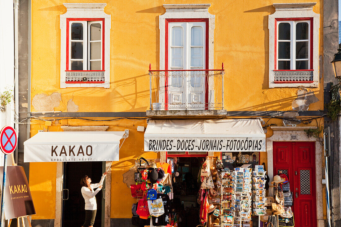 Ein Ladenbesitzer hebt die Markise über die Auslagen vor dem Geschäft; Faro Algarve Portugal