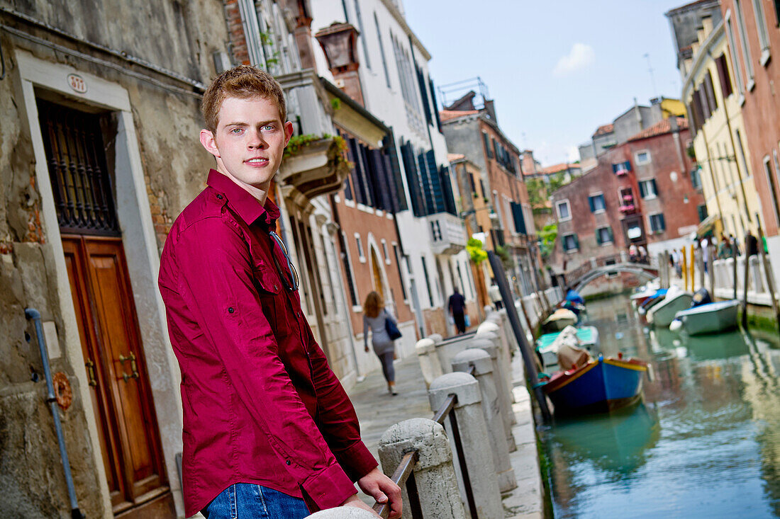 A Young Man Standing At A Railing On A Canal; Venice Italy