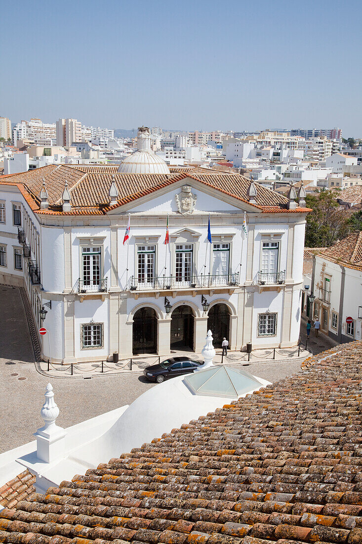 Ein Auto parkt vor einem weißen Gebäude mit der Stadt im Hintergrund; Faro Algarve Portugal