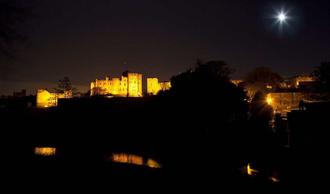 Der Vollmond leuchtet hell über einer nachts beleuchteten Stadt; Alnwick Northumberland England