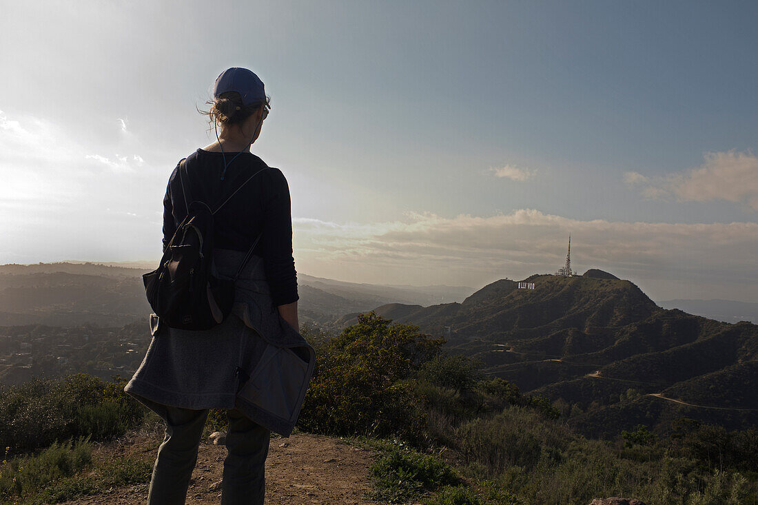 Rear View of Hiker viewing Hollywood Sign and Santa Monica Mountains in the Distance, Los Angeles, California, USA