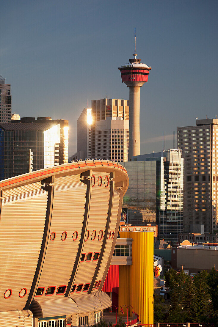 Calgary Saddledome With The Calgary Tower And Buildings In Background Reflecting Light At Sunrise; Calgary Alberta Canada