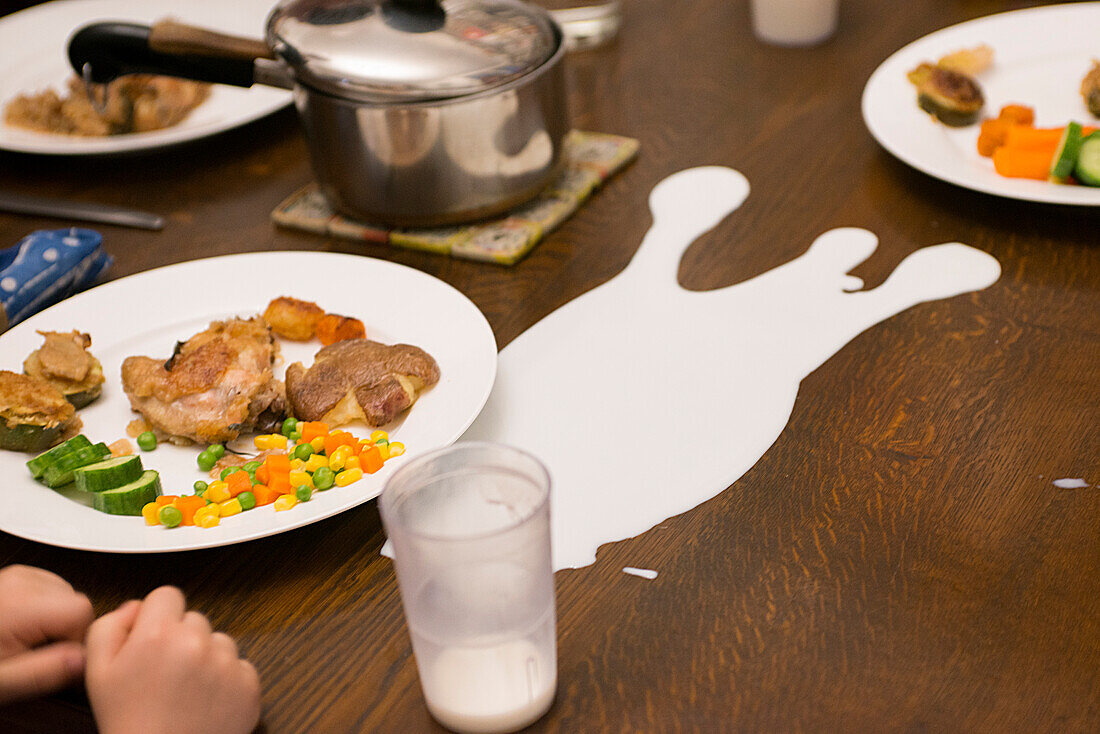 Tasse mit verschütteter Milch auf dem Esstisch