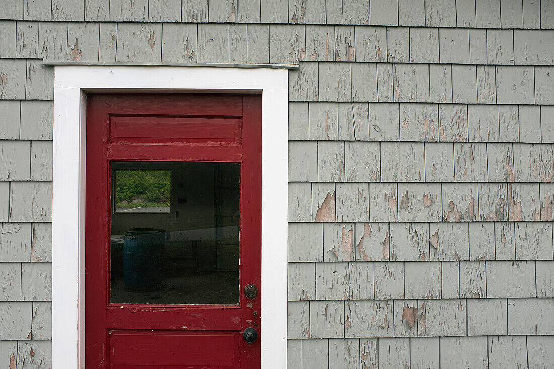 Rote Tür und verwitterte graue Wand