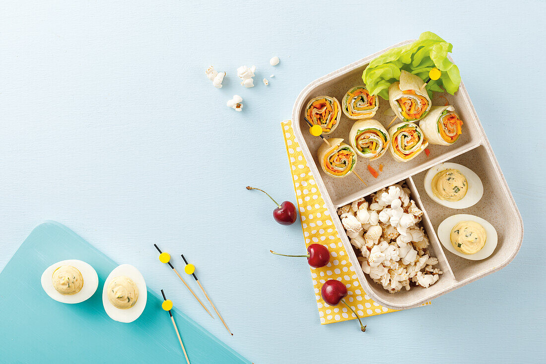 Lunchbox with tortilla wraps, eggs and popcorn