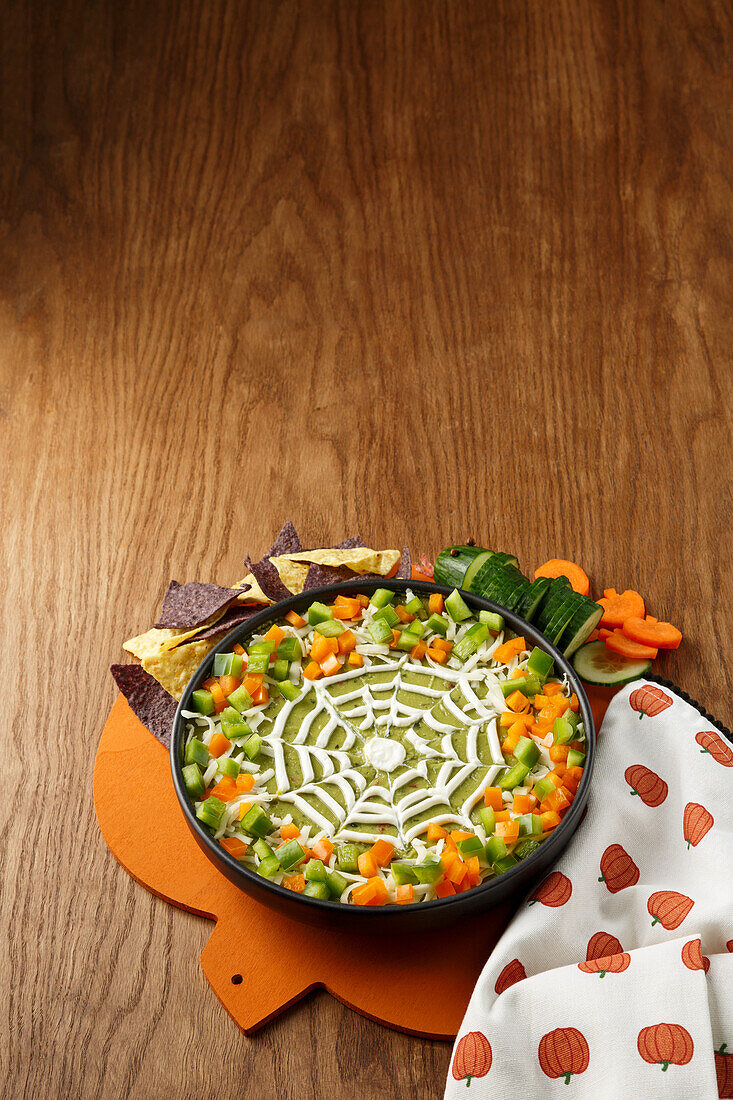 Green Halloween dip with peppers and sour cream spider web