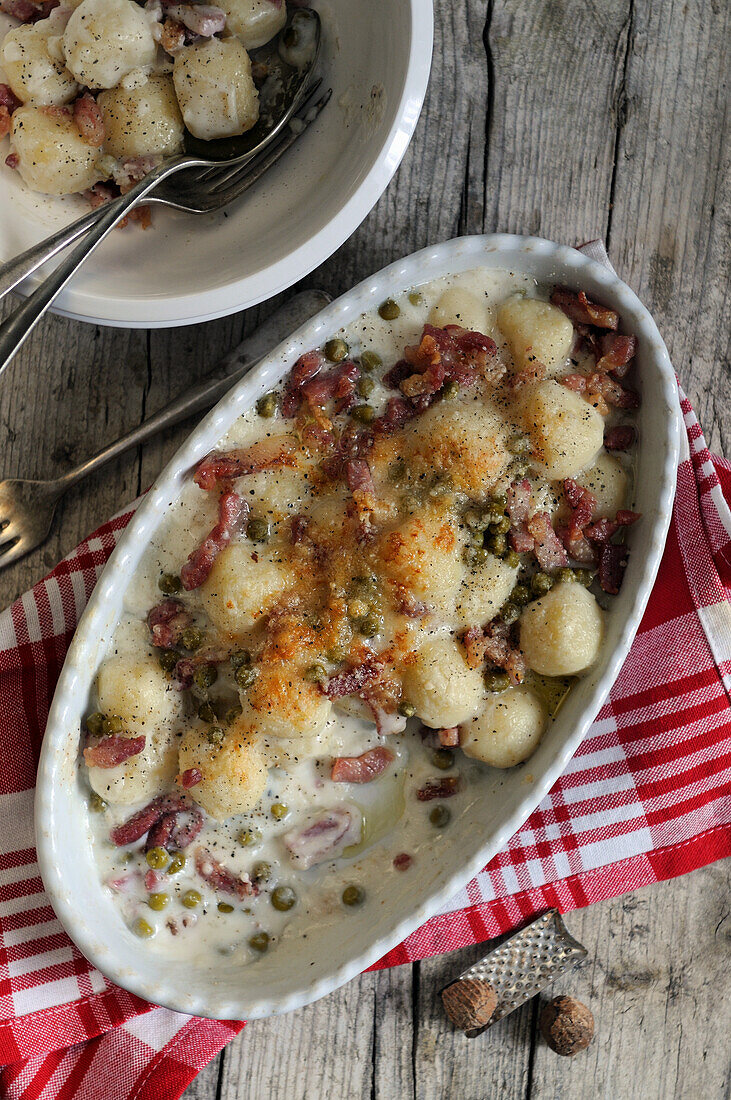 Homemade Italian gnocchi with creamy cheese, peas and pancetta sauce