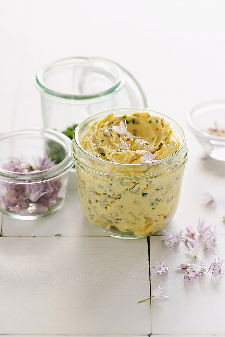 Aufgeschlagene Kräuterbutter mit Schnittlauchblüten und Knoblauch