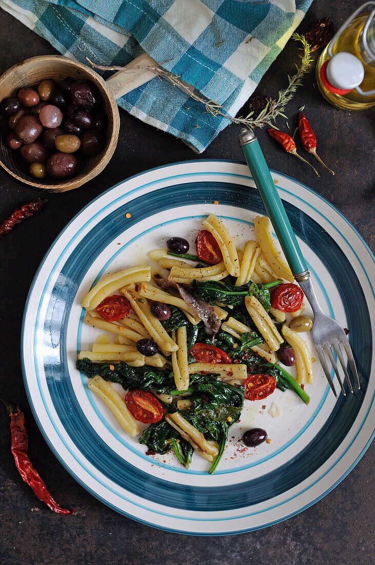 Casarecce pasta with olives, anchovies, spinach and tomatoes