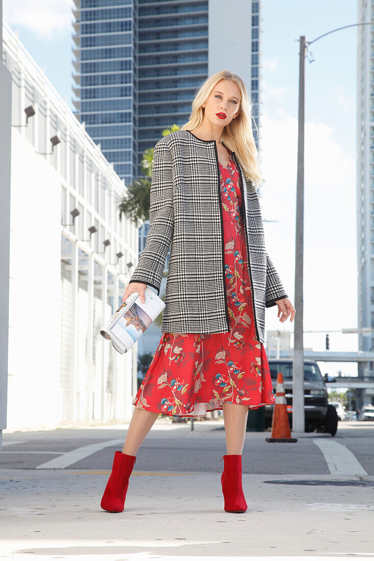 Young blonde woman in a red floral dress and checked coat