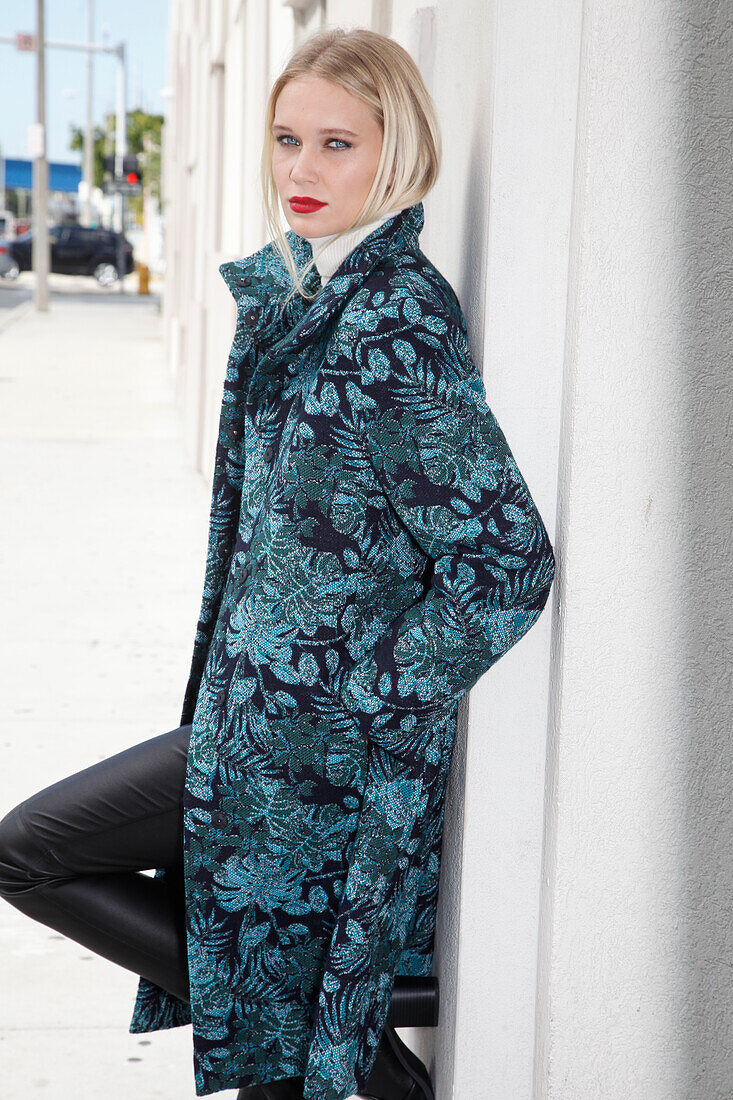 Young blond woman in transitional coat with leaf jacquard