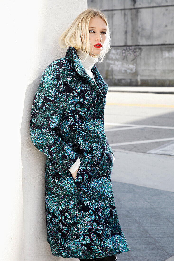 Young blond woman in transitional coat with leaf jacquard