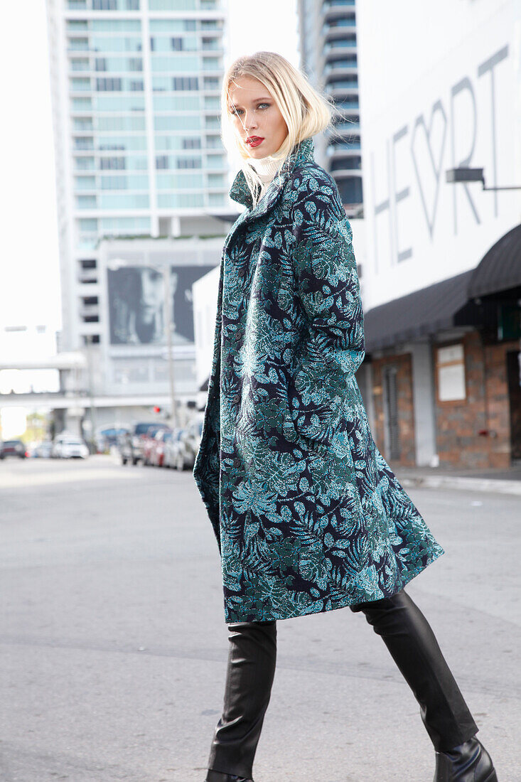 Young blond woman in transitional coat with leaf jacquard