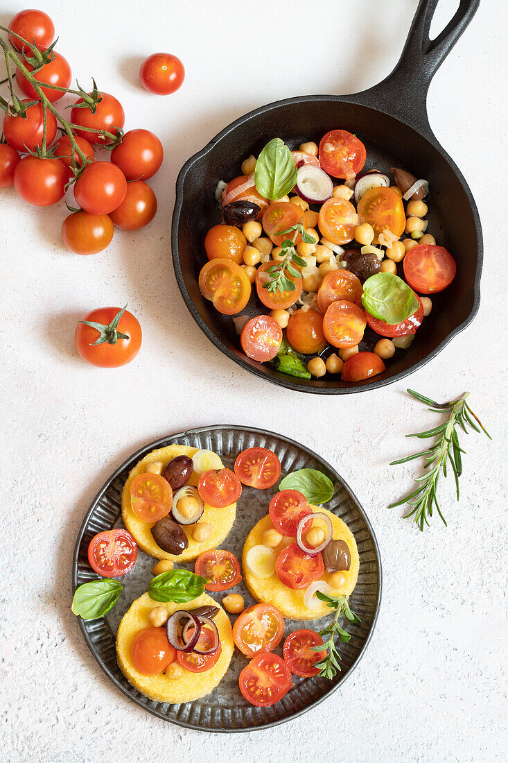 Polenta slices topped with cherry tomatoes, chickpeas and spring onions