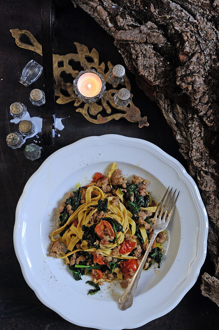 Homemade tagliatelle with sausage, spinach and tomatoes