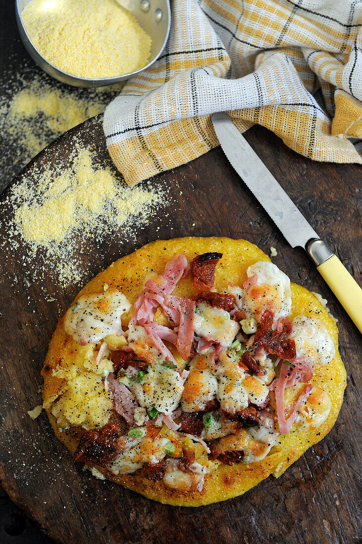 Polenta pizza with mozarella, ham and onions