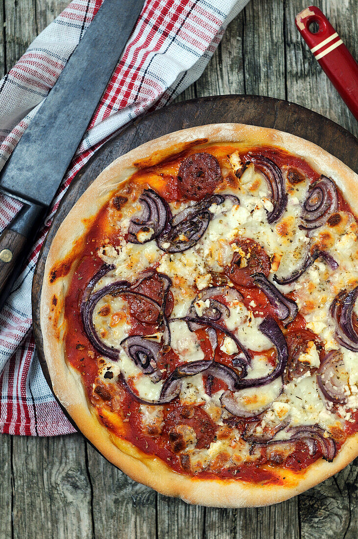 Hausgemachte Pizza mit Mozzarella, Salami und Zwiebeln