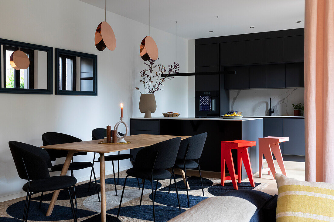 Open-plan living room with dining table, black kitchen and copper-coloured pendant lights