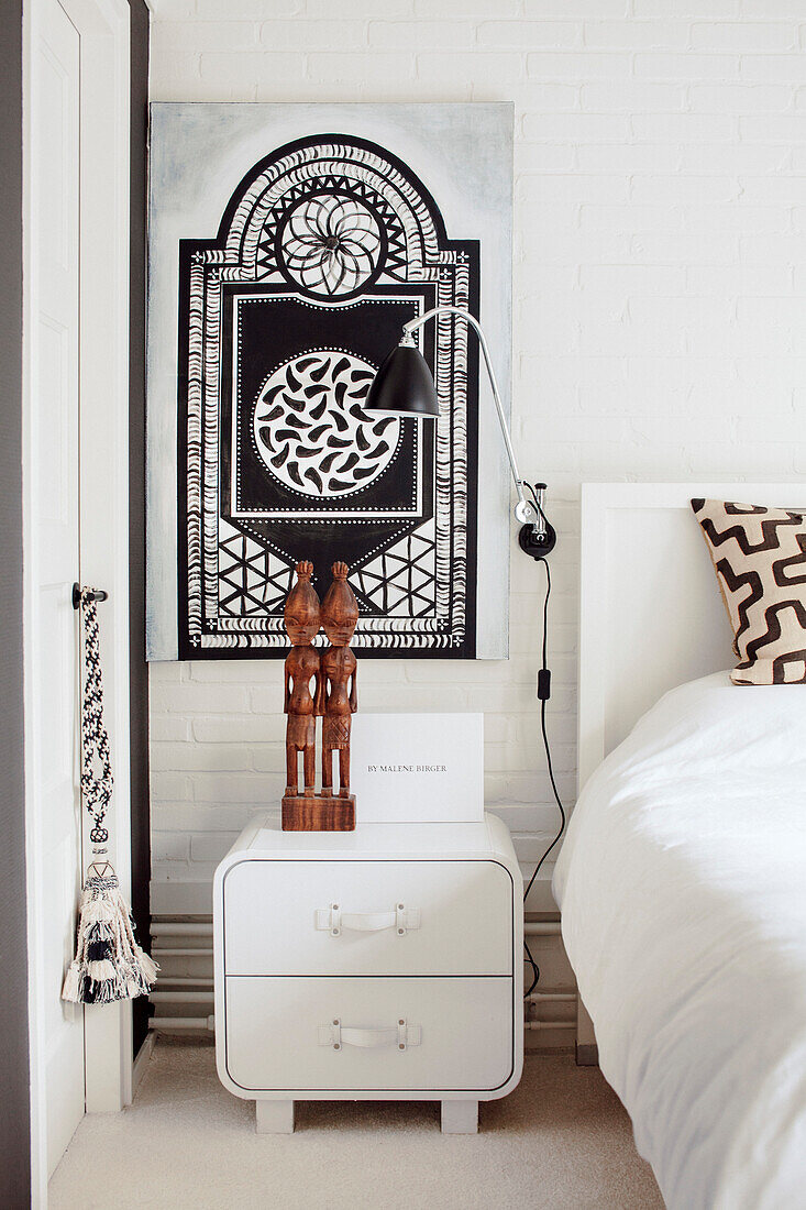 Bedroom with mural, white bedside table and wall lamp