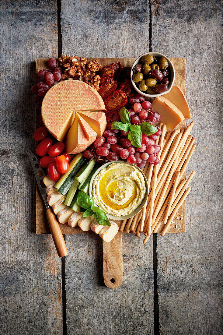 Cheese platter with olives, dip, tomatoes, cucumber, grapes and walnuts