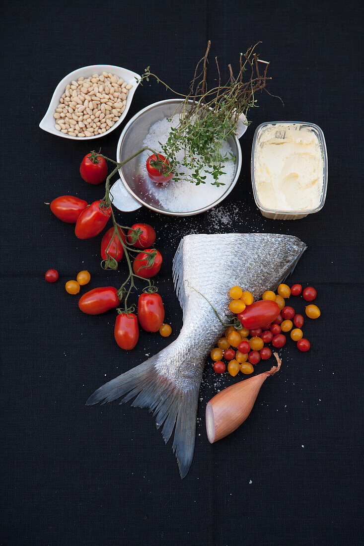 Ingredients for fish dish: sea bass, tomatoes, butter, and pine nuts