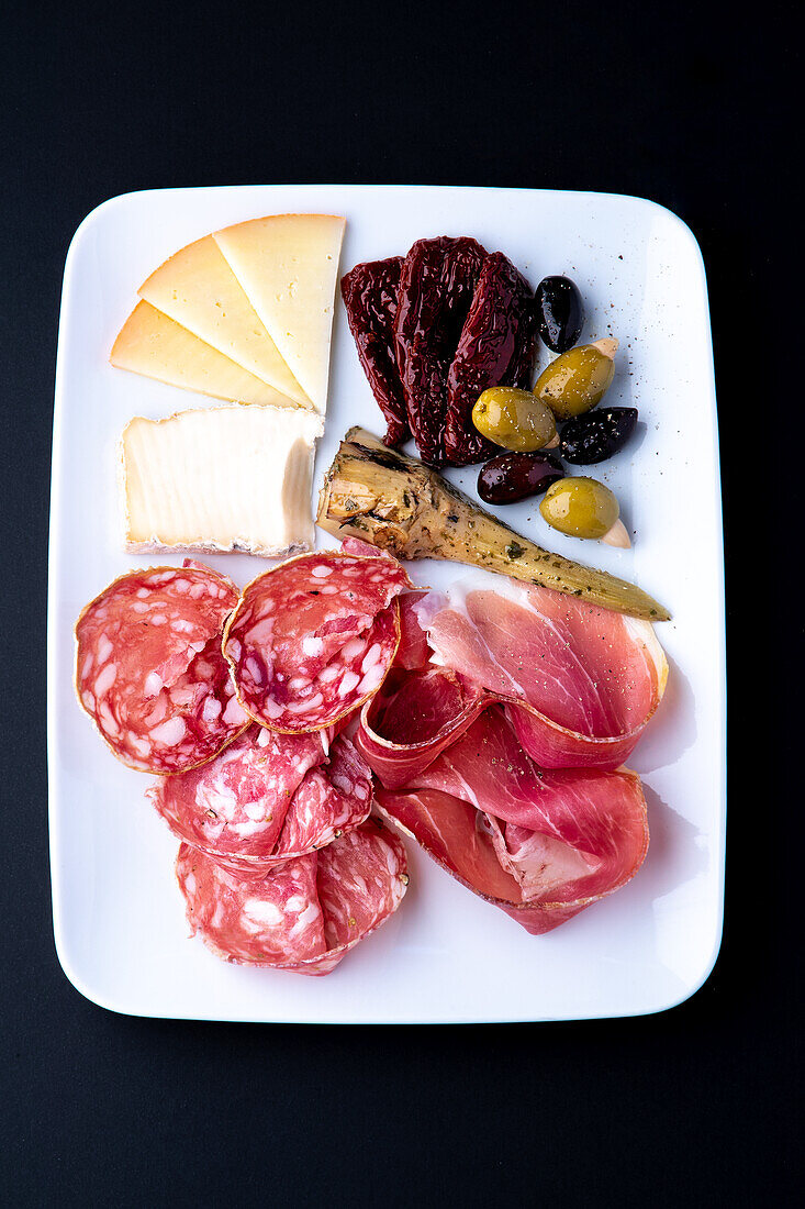 Tapas with artichoke, Parma ham, salami, cheese, dried tomatoes, and olives