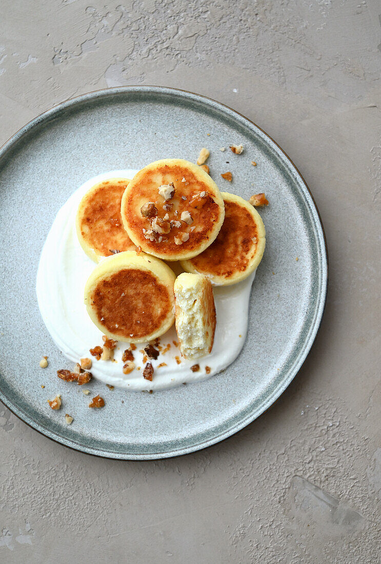 Syrniki (Russian cream cheese pancakes) with sour cream and caramelized nuts