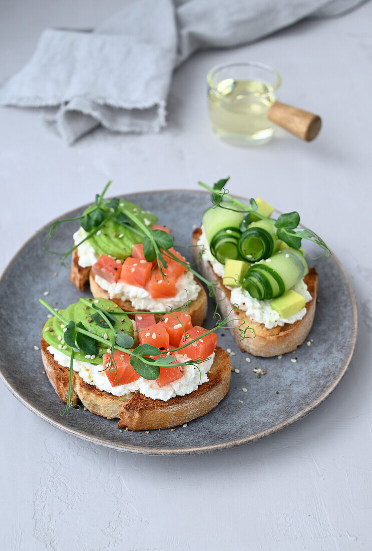 Crostini with cream cheese, salmon, avocado, cucumber and pea shoots