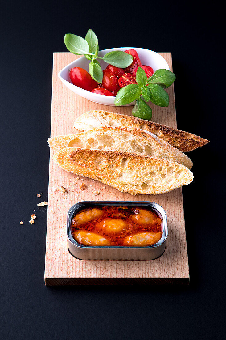 Canned mussels in tomato sauce with toasted bread and tomatoes with basil