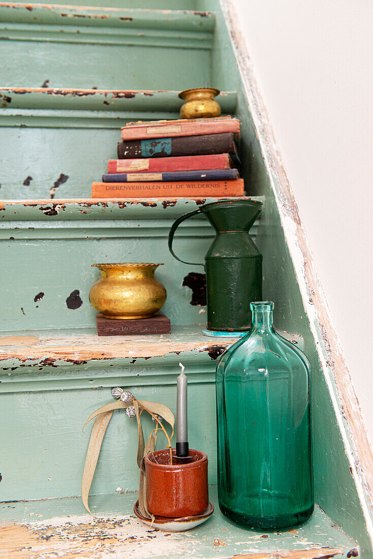 Grüne Glasflasche und Bücherstapel auf alter Holztreppe