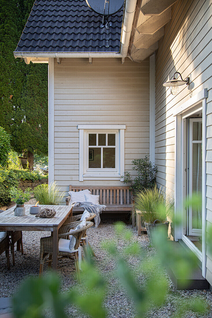 View of terrace with table and bench in front of house with wooden paneling