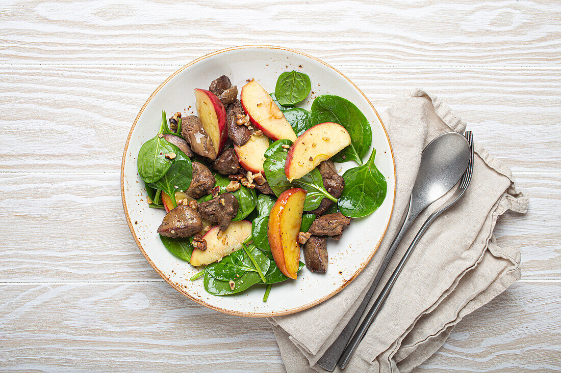 Gesunder Salat mit eisenreichen Zutaten: Hühnerleber, Äpfel, Spinat und Walnüsse