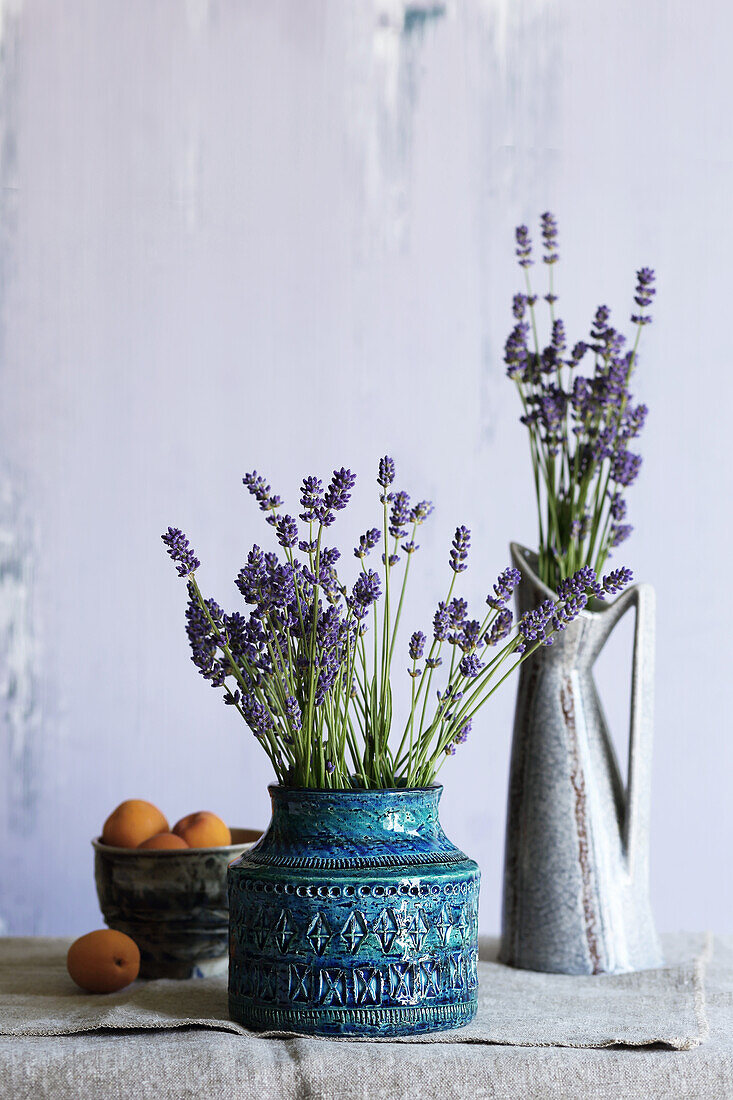 Lavendel in zwei Vintage Keramik-Vasen, daneben eine Schale mit Aprikosen