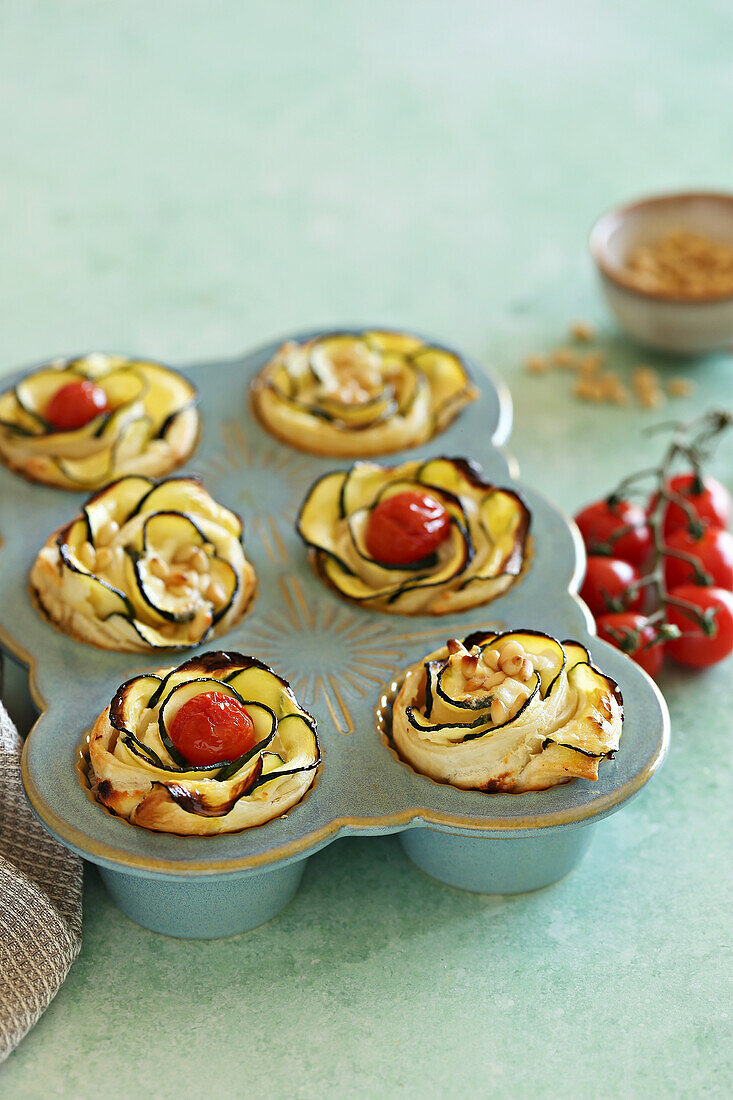 Puff pastry tartlets with zucchini, cherry tomatoes, cream cheese, and pine nuts