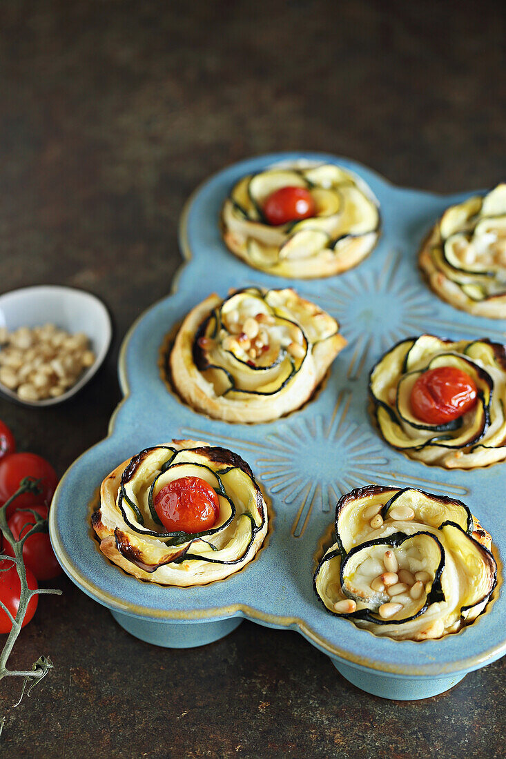 Puff pastry tartlets with zucchini, cherry tomatoes, cream cheese, and pine nuts