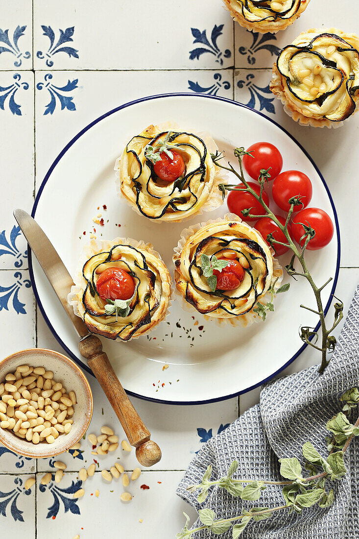 Puff pastry tartlets with zucchini, cherry tomatoes, cream cheese and pine nuts