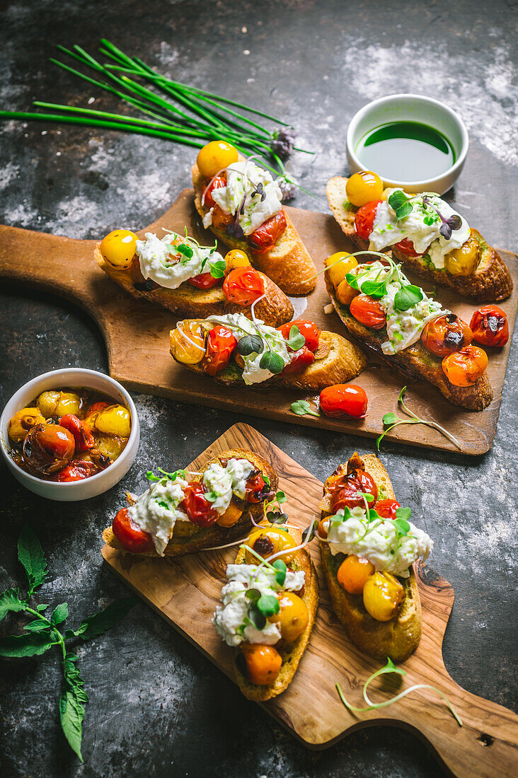 Crostini with grilled cherry tomatoes, burrata cheese, and chive oil